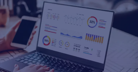 Laptop displaying a business intelligence dashboard with charts, KPIs, and performance metrics on a desk.