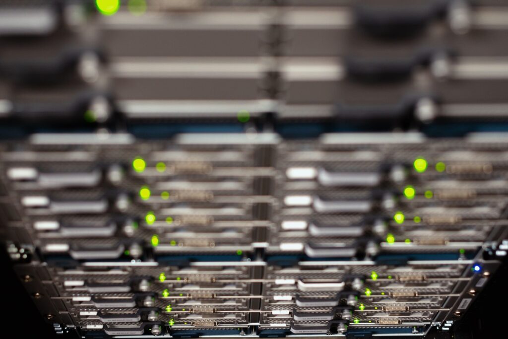 Blurred view of rack-mounted servers in a data center with numerous green activity LEDs