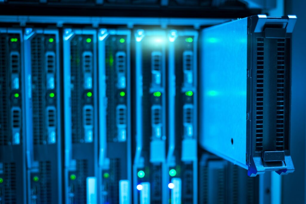 Rows of rack-mounted servers in a data center with blue lighting and green status LEDs.
