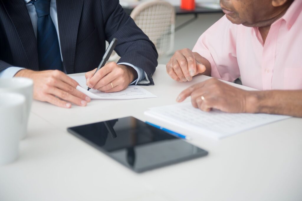 Two professionals signing documents across a desk