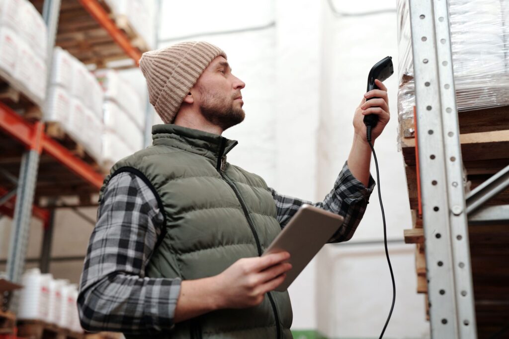 Warehouse worker checking stock with a handheld barcode scanner and a tablet