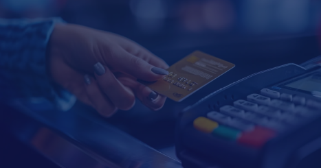 Person swiping a gold credit card through a payment terminal at a checkout.
