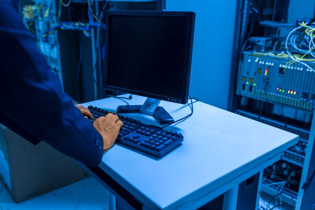 IT technician at a console in a blue-lit data center server room